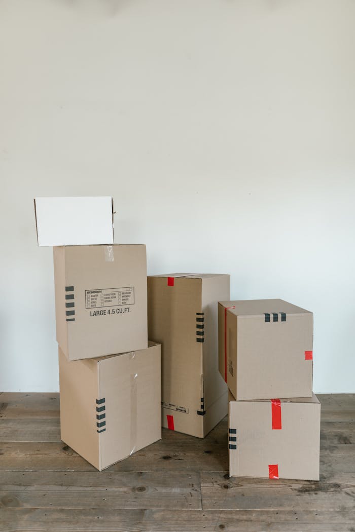 about-us A stack of various cardboard boxes ready for moving or shipping indoors.